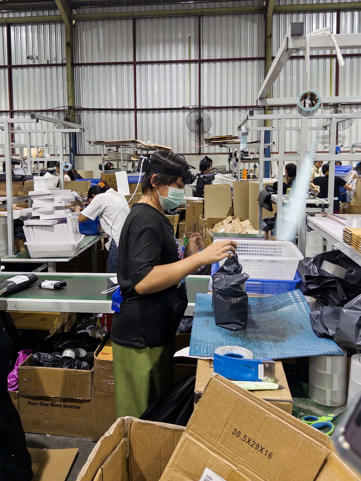 A Luckey collector wearing a head-mounted camera while packing products on a factory production line